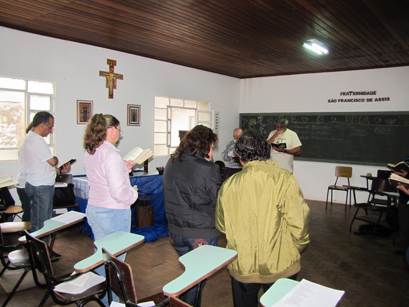 Irmãos em pé rezando juntos durante um encontro da fraternidade